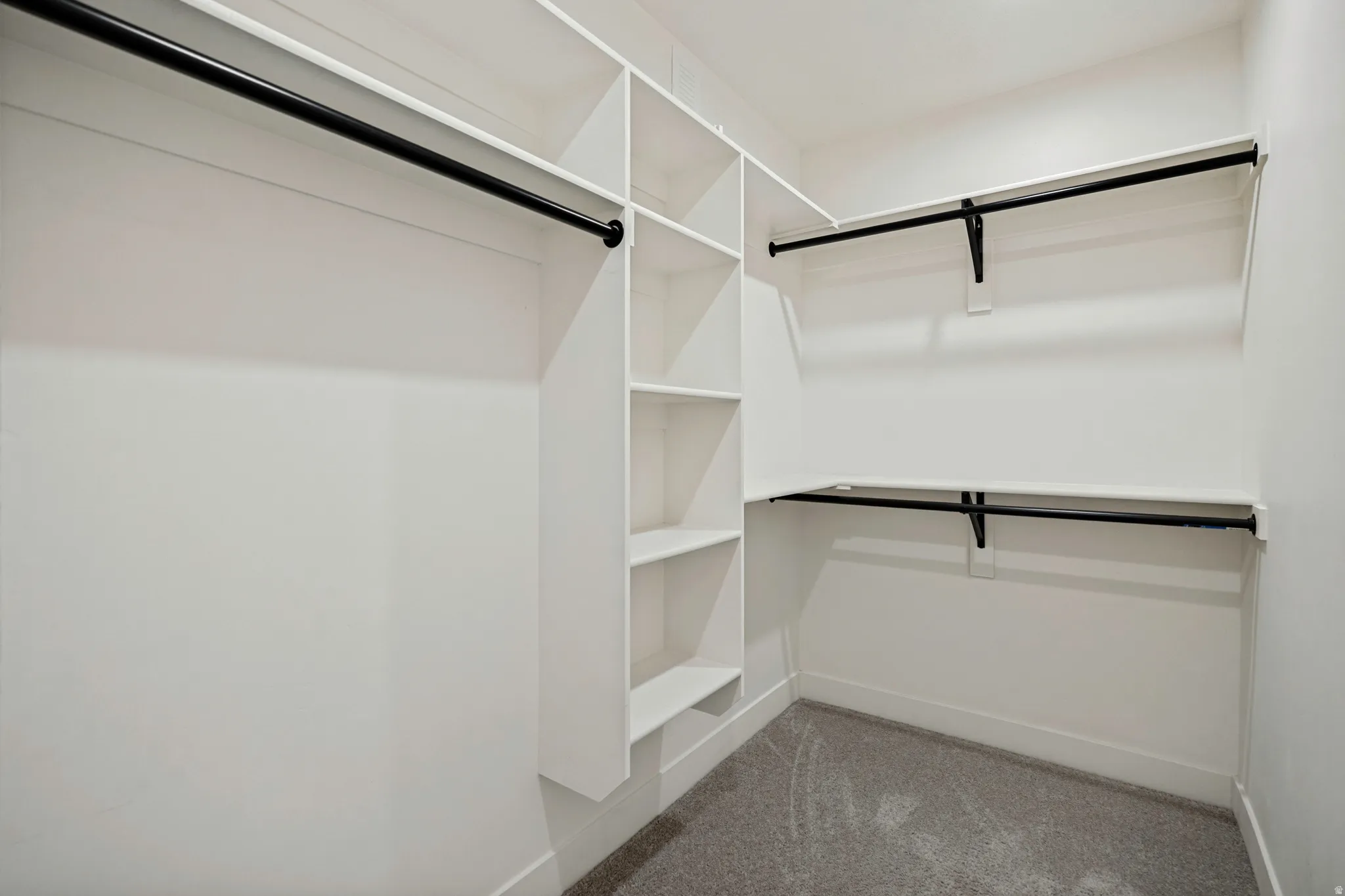 Built-in shelving, multiple hanging rods, and light-colored carpeting