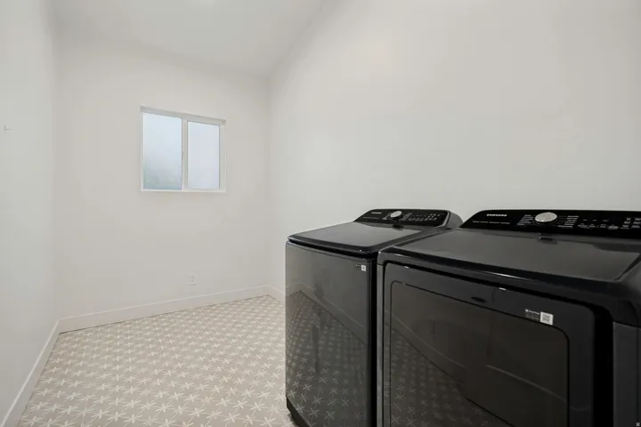 Dedicated laundry space featuring a window, patterned flooring, and a pair of dark-finished appliances