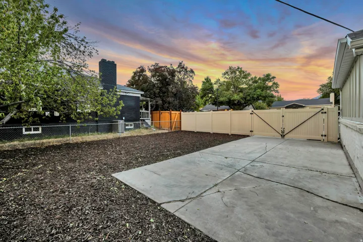 Expansive concrete patio with a large gate, bordered by a full-height privacy fence