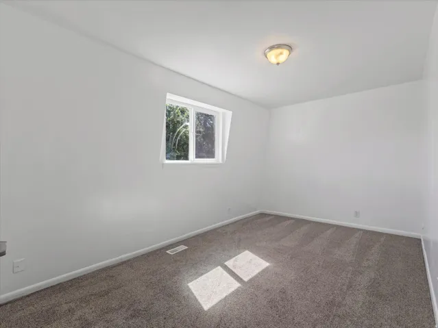Neutral-toned carpeting, white walls, and a window with natural light
