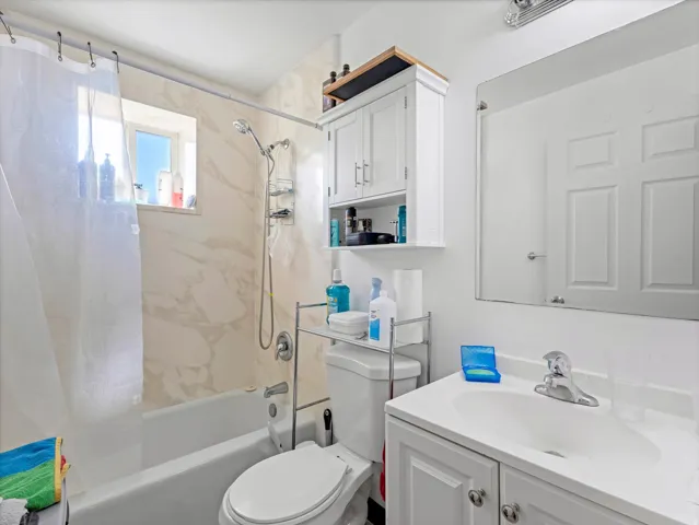 Bathtub with a single-handle faucet and integrated shower head, marble-look shower surround, and a fixed window