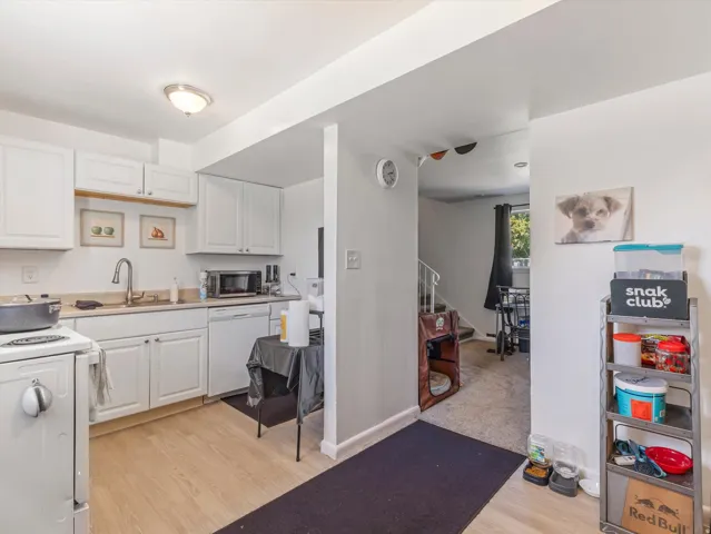 Kitchen featuring white cabinetry, light wood-finish flooring, a stainless steel sink with a gooseneck faucet, and a built-in dishwasher