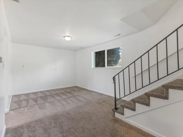 Carpeted flooring, white walls, flush mount lighting, and a window
