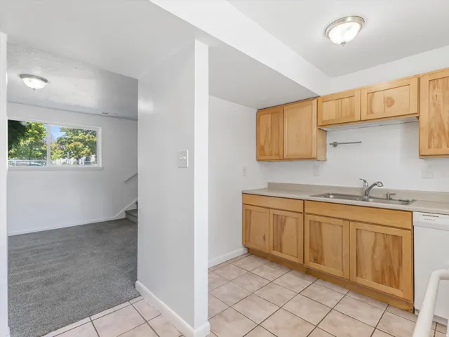 Kitchen area featuring wood cabinetry, a stainless steel sink, and light-toned floor tiling