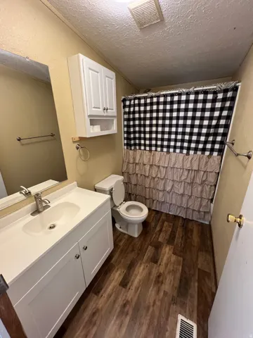 White vanity with an integrated sink, polished chrome faucet, and wood-finish flooring