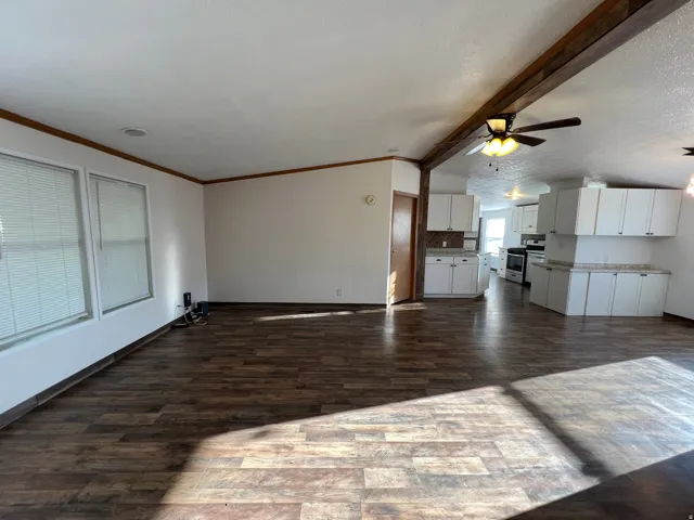 Open concept living area with wood-finish flooring, white walls, and a ceiling fan