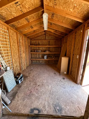 Vaulted wood-finish ceiling with exposed beams, built-in shelving, and overhead fluorescent lighting