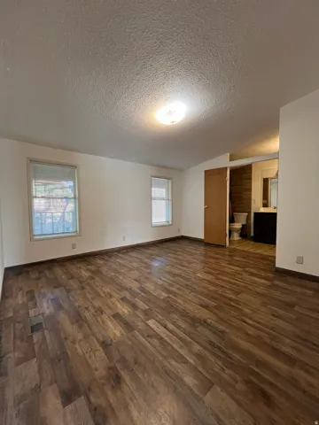 Wood-finish flooring throughout, two windows with blinds, recessed lighting fixture, and a neutral wall palette