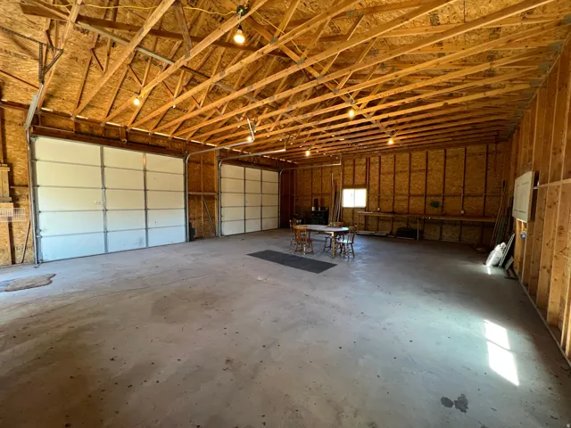 Spacious multi-bay structure featuring a concrete floor, exposed wood beam ceiling, and multiple overhead doors