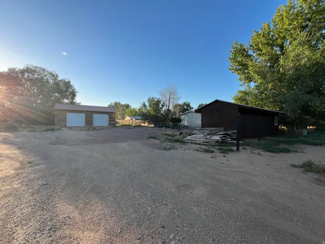 Gravel driveway with two detached structures featuring metal roofs