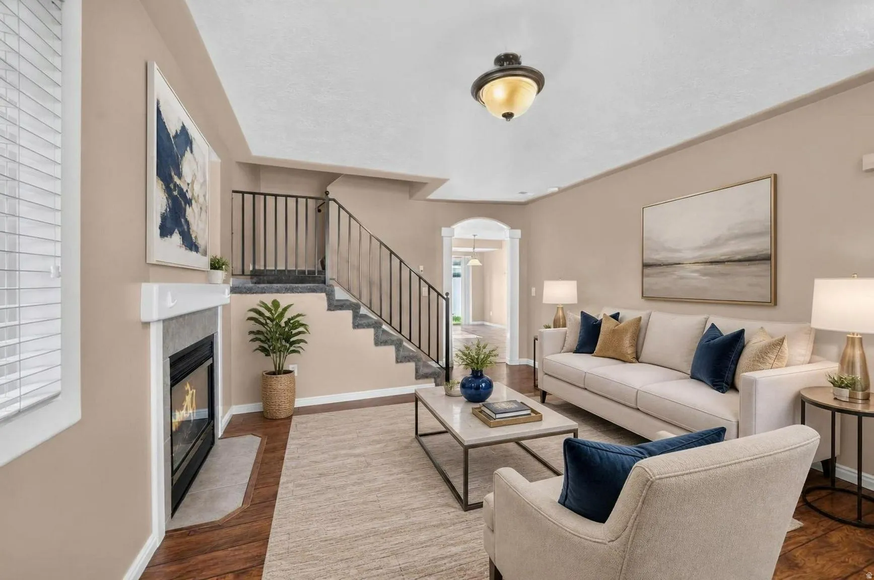 Hardwood-finish flooring, built-in fireplace, staircase with metal railings, arched doorway, and semi-flush mount lighting
