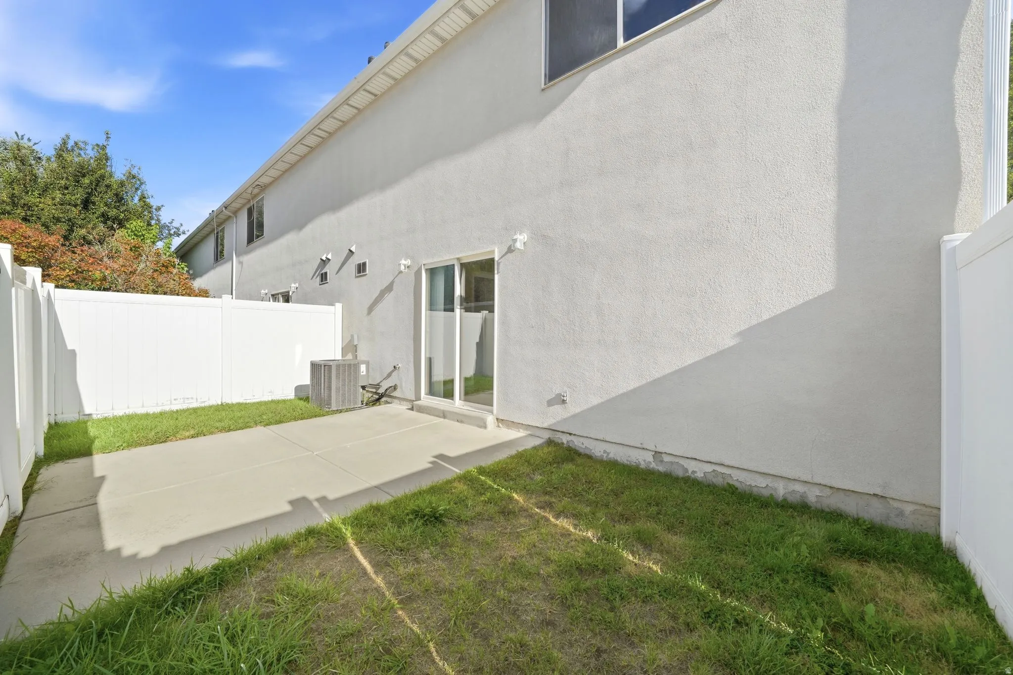 Private outdoor space featuring a concrete patio, vinyl fencing, and a sliding glass door