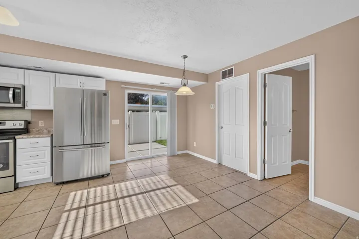 Kitchen with white cabinetry, stainless steel appliances, tile flooring, and sliding glass doors to a patio