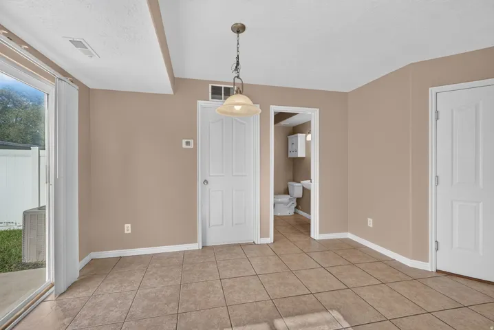 Spacious primary living area showcasing tile flooring, recessed ceiling detail, and abundant natural light from sliding glass doors