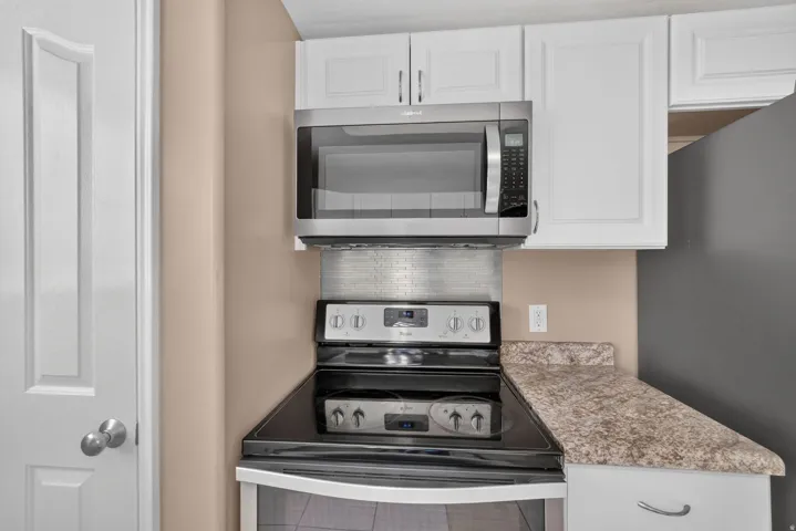 White shaker-style cabinetry, stainless steel microwave, black electric range with stainless steel elements, laminate countertops