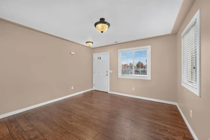 Wood-finish flooring, white trim details, multiple windows, and two ceiling-mounted light fixtures