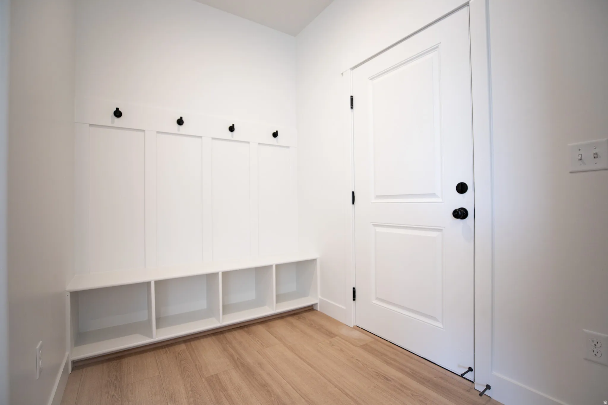 Mudroom adjacent to garage with built-in bench, cubbies and coat hooks.