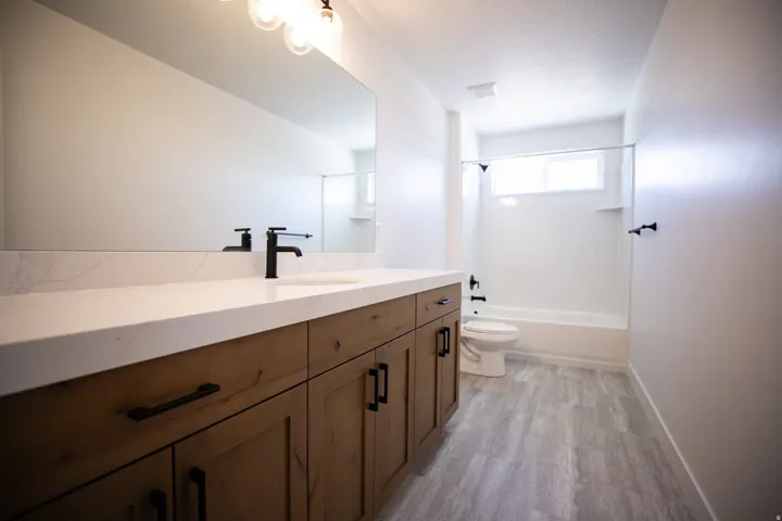 Full secondary bath with extra-long vanity, stained wood cabinets and quartz slab countertop.