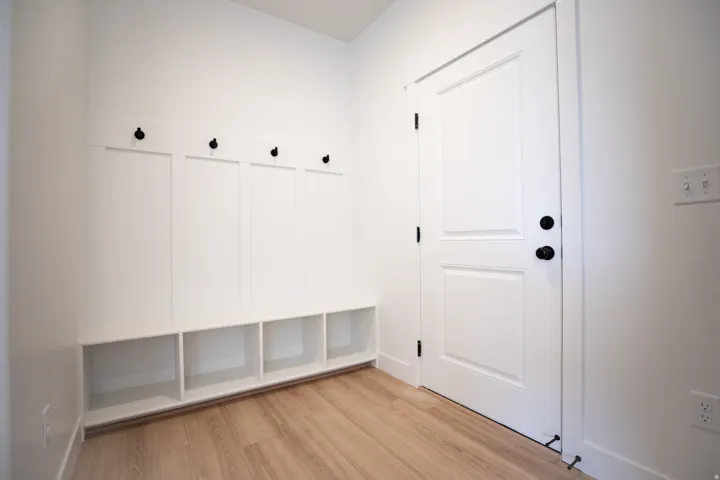 Mudroom adjacent to garage with built-in bench, cubbies and coat hooks.