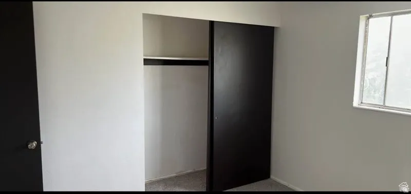 Sliding closet doors, built-in closet shelving, and a window with a metal frame