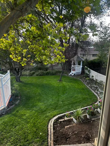 Expansive lawn with mature trees and a white gazebo
