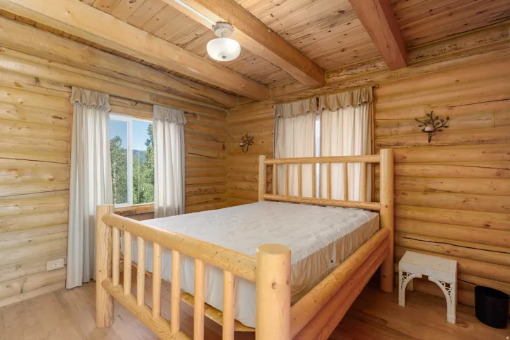Log wall construction with exposed ceiling beams, wood-finish flooring, and a single window