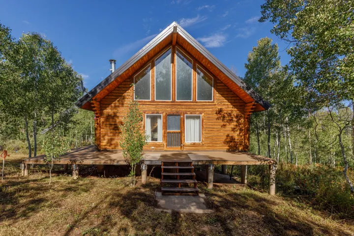 Log cabin exterior with an A-frame roof and prominent front-facing windows