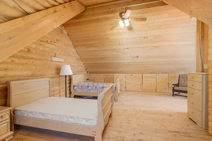 Wood-paneled walls and ceiling, exposed structural beams, ceiling fan with light kit, and built-in storage cabinets