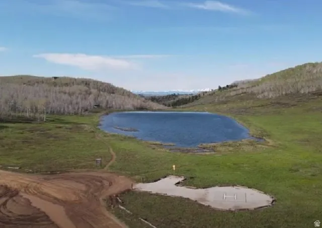Expansive land with a natural body of water, surrounded by rolling hills and distant snow-capped mountains