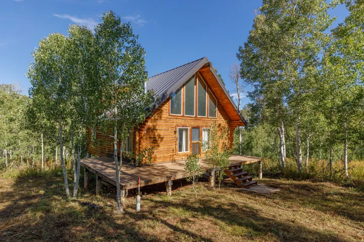 Wood-sided cabin with a pitched metal roof, expansive wood deck, and a tall window array