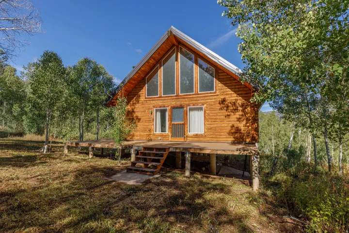 Log cabin exterior with a pitched roof, prominent gable windows, and an elevated wood deck