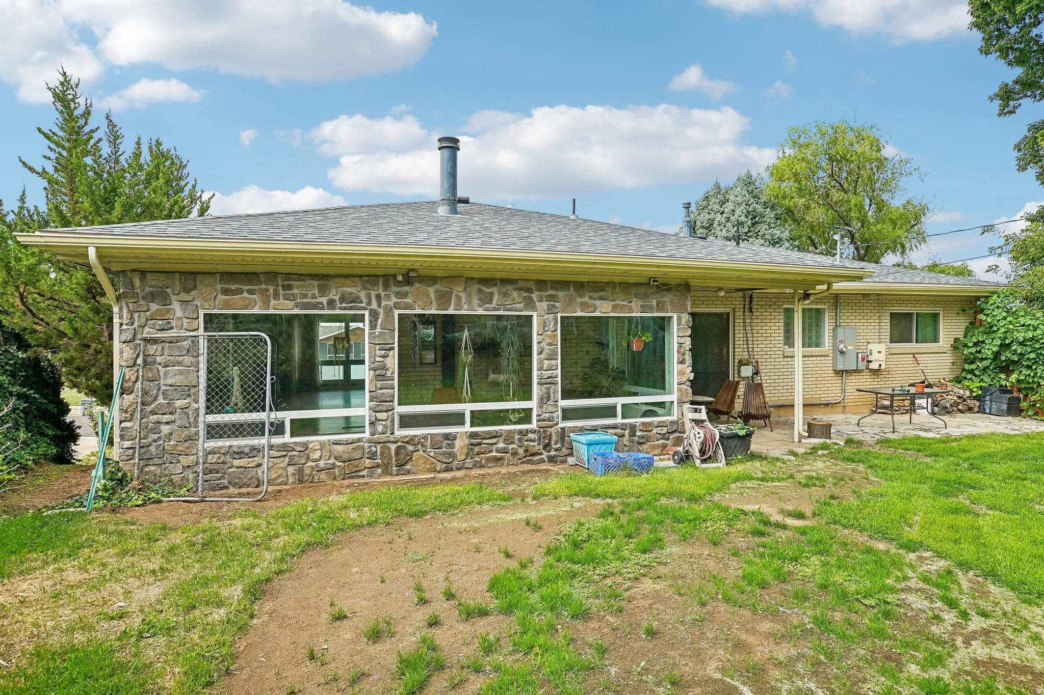 Stone exterior featuring large windows and a covered patio area