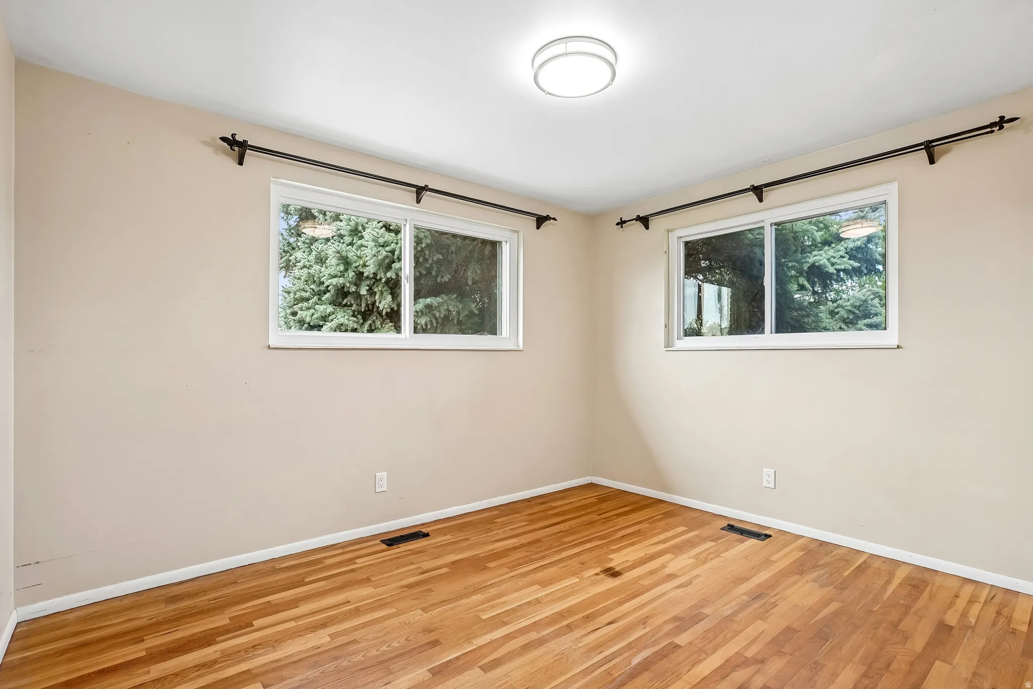 Hardwood flooring, two windows, recessed lighting, and neutral wall tones