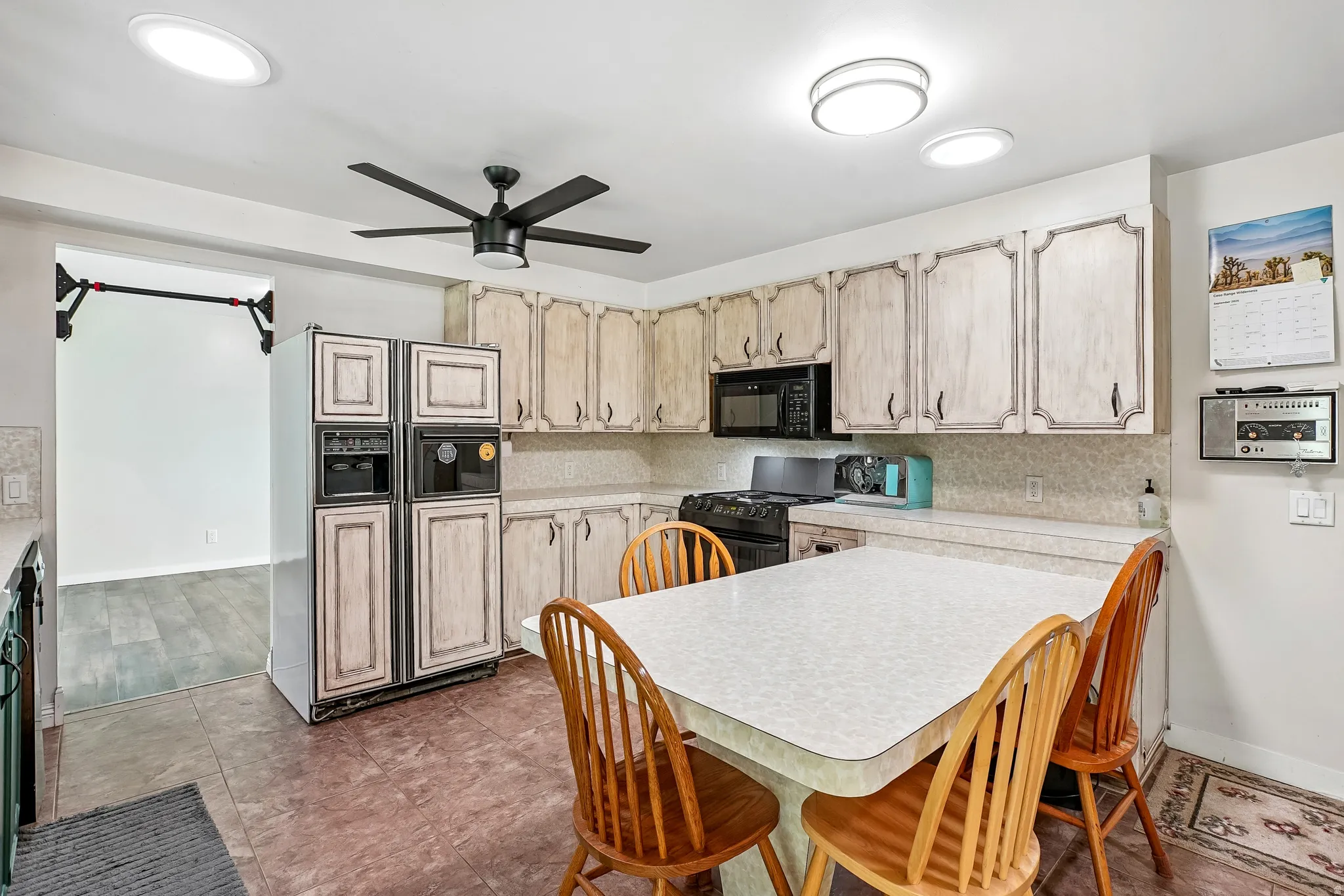 Kitchen featuring wood-finish cabinetry, black appliances, tile flooring, and recessed lighting