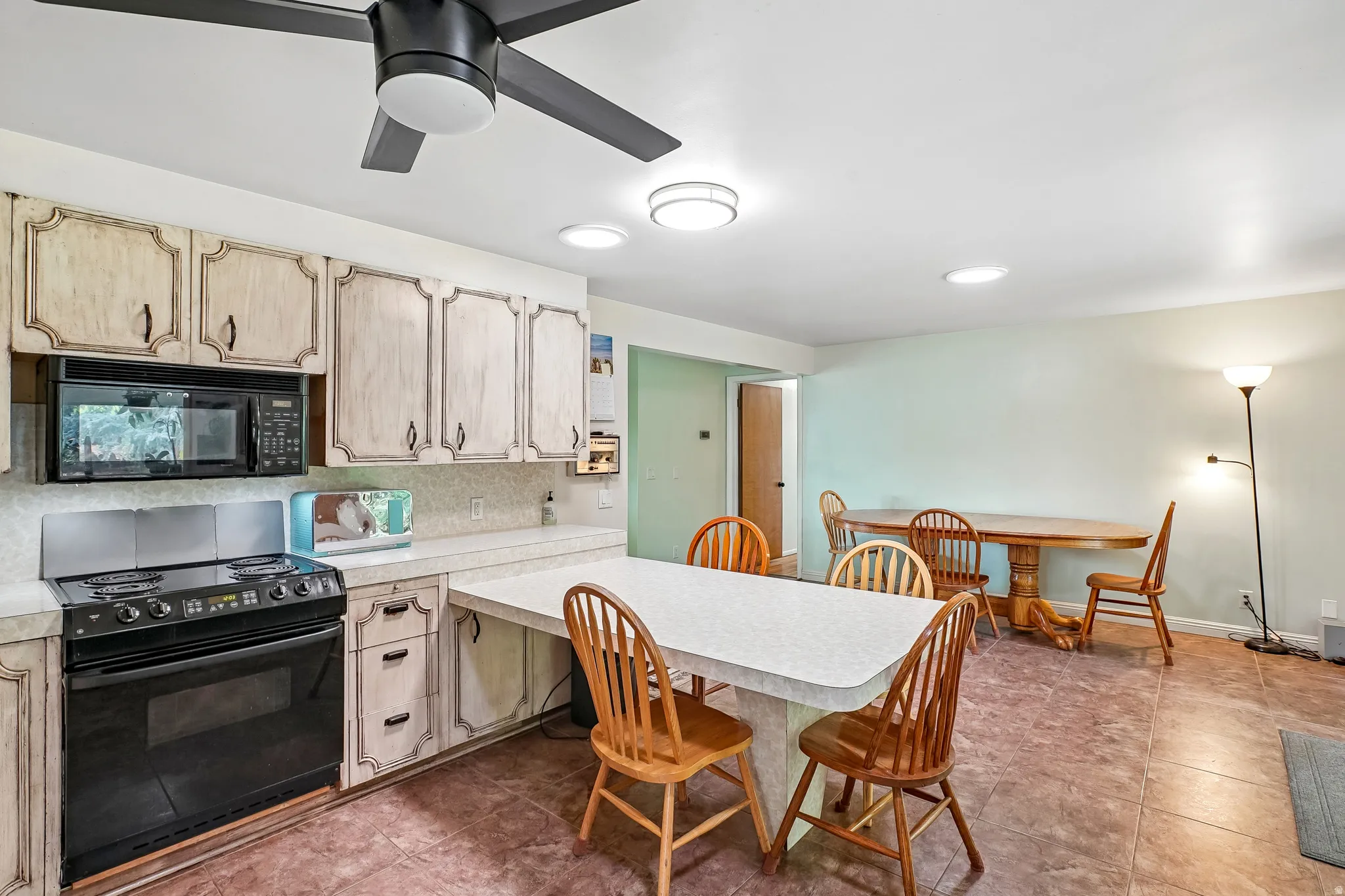 Kitchen with light-toned cabinetry, built-in microwave, and electric range