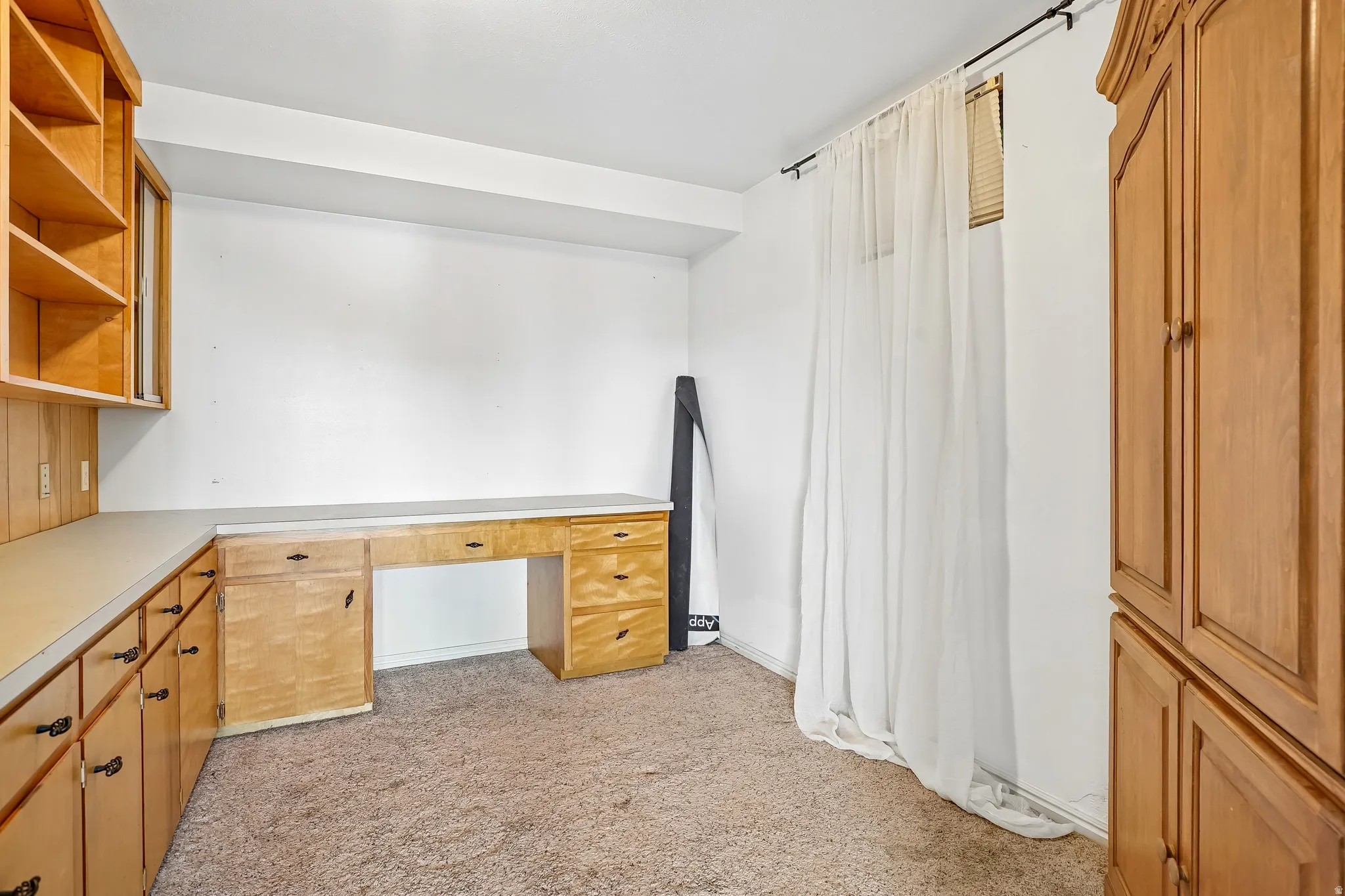 Built-in desk with drawers, extensive cabinetry, open shelving, and neutral wall tones