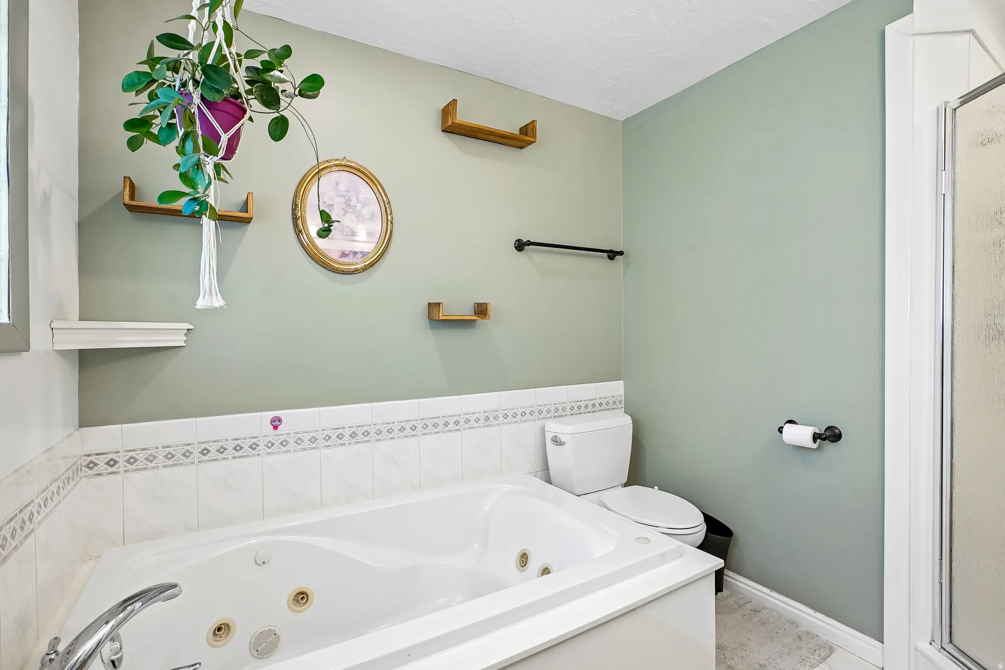 Built-in jetted tub with chrome fixtures, surrounded by white tile with a decorative accent band