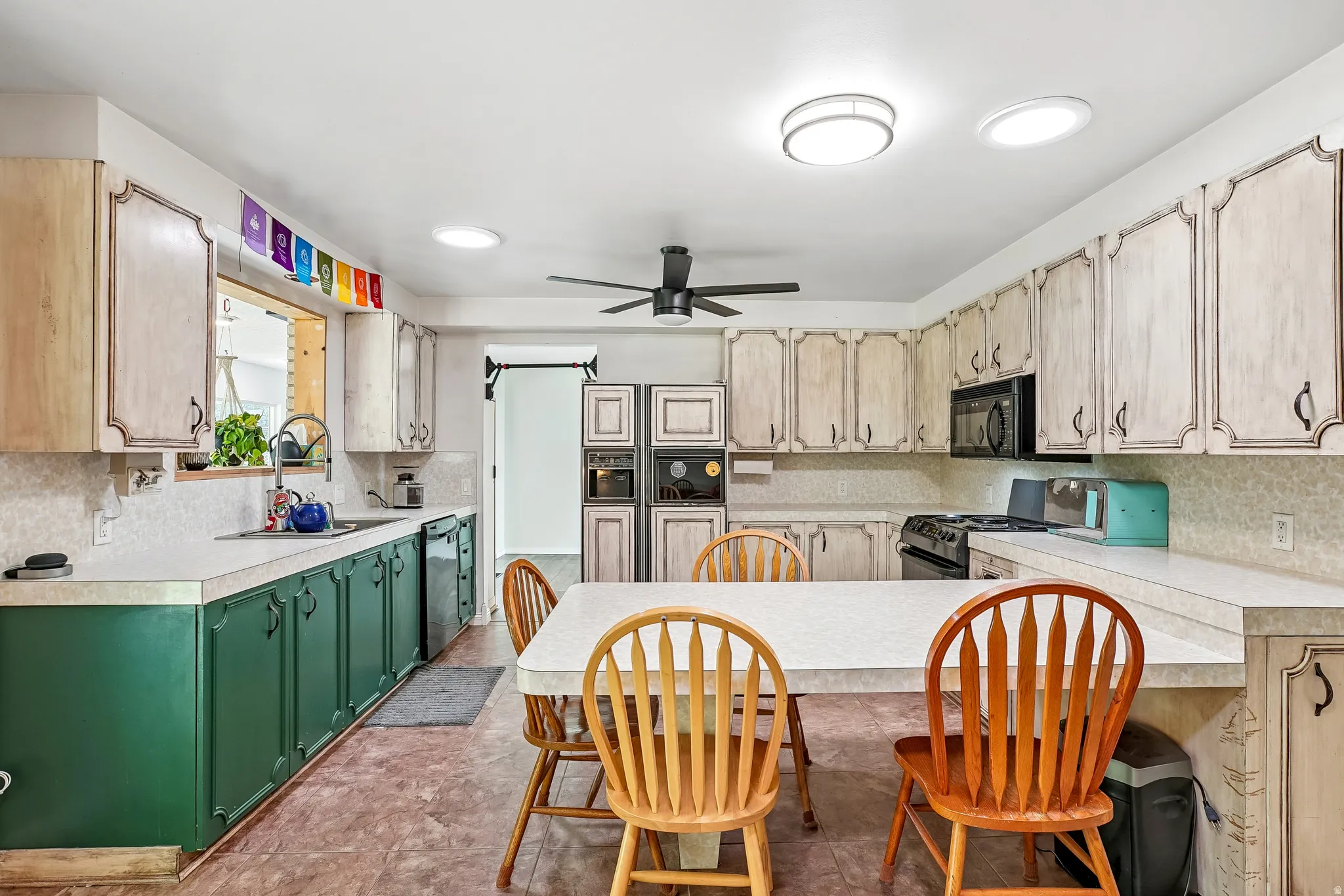 U-shaped kitchen with light-toned upper cabinetry, green lower cabinetry, and light countertops