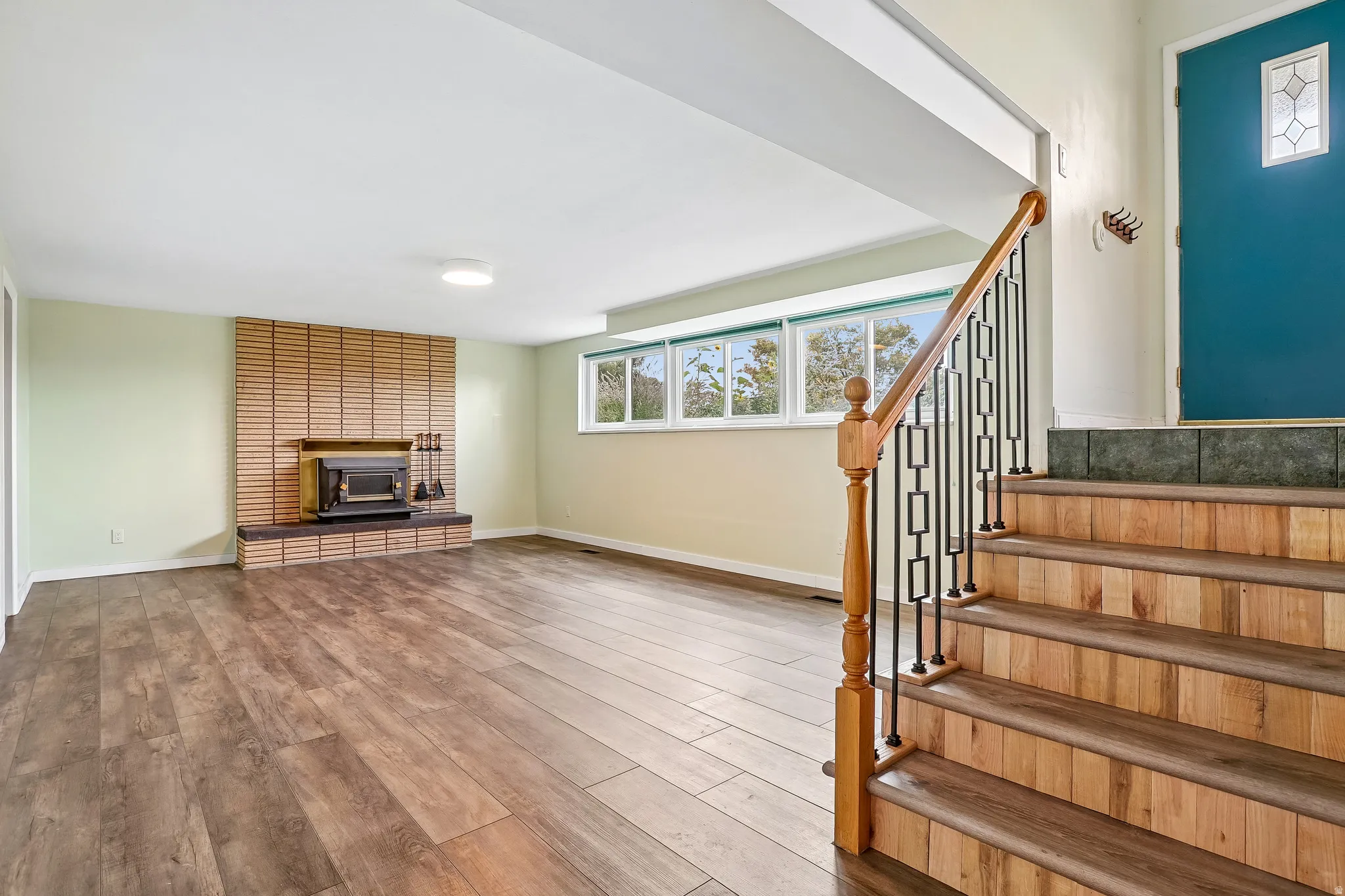 Lower-level living area featuring wood-finish flooring, a brick fireplace, and multiple windows