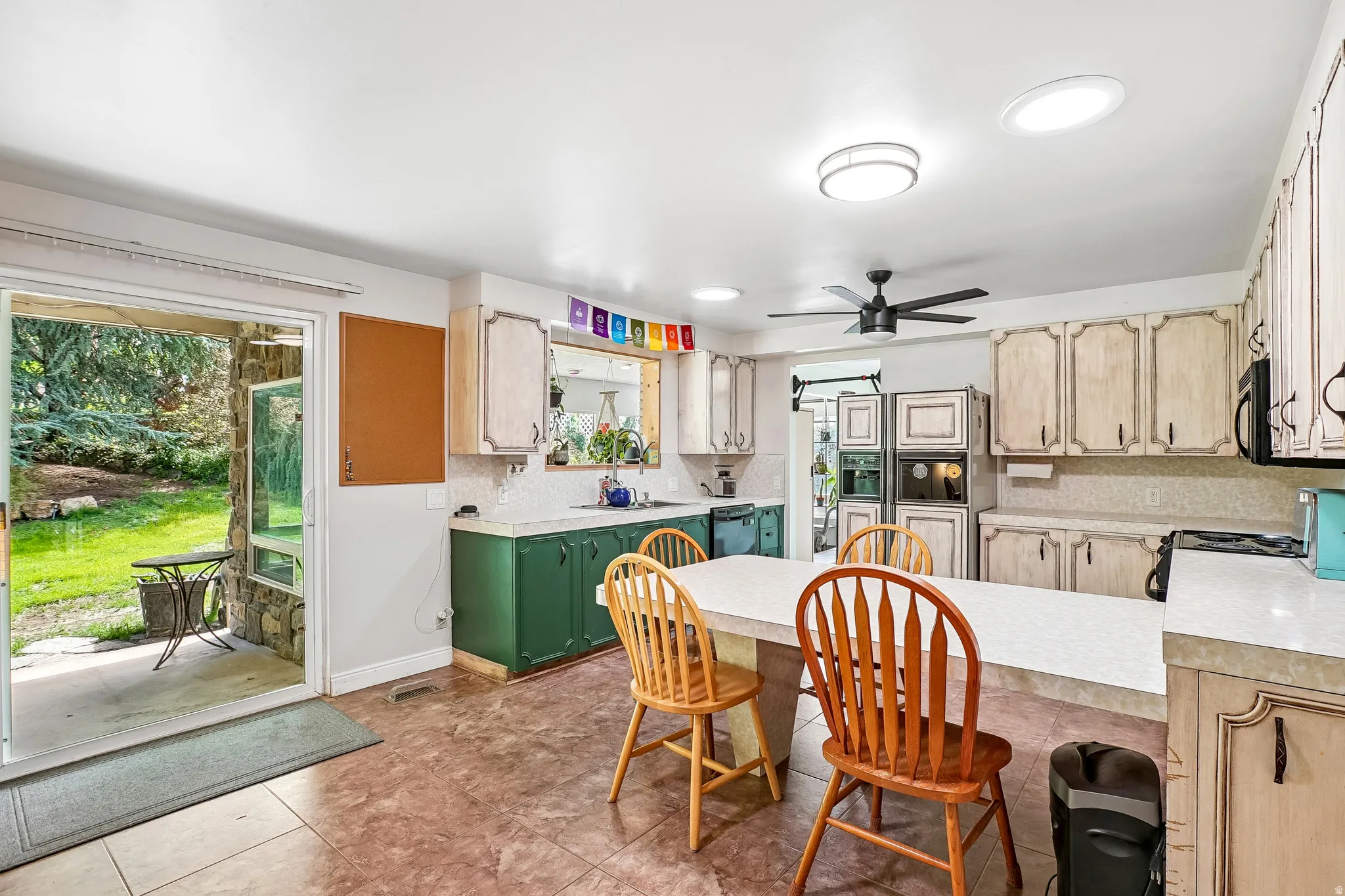 Kitchen featuring a large center island, built-in double ovens, and a ceiling fan