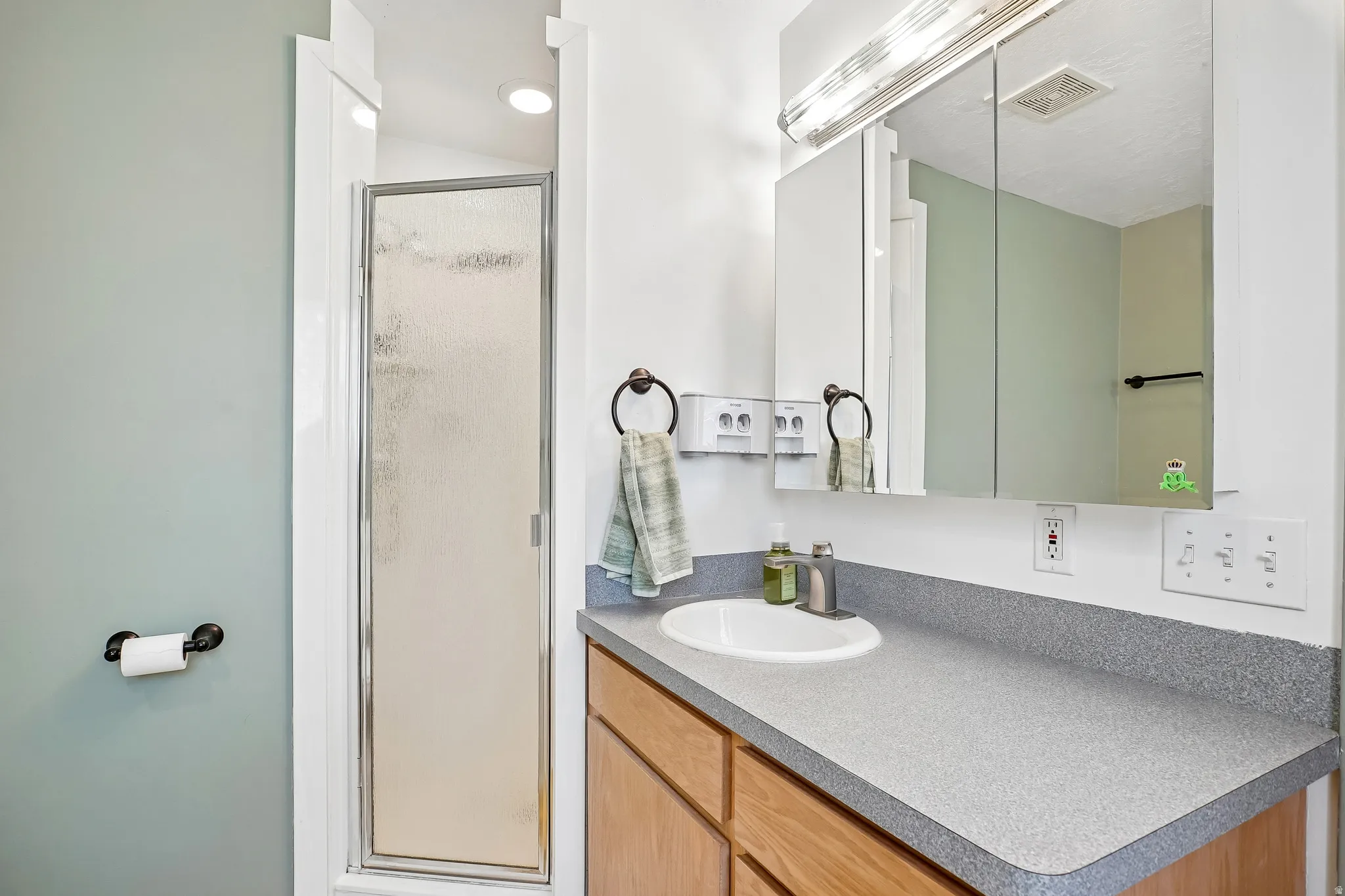 Bathroom vanity with a composite countertop, an integrated sink, and an overhead mirrored medicine cabinet