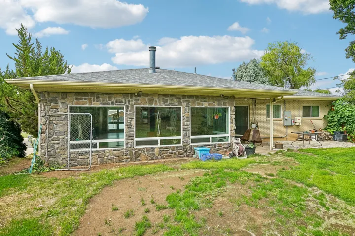 Stone exterior featuring large windows and a covered patio area
