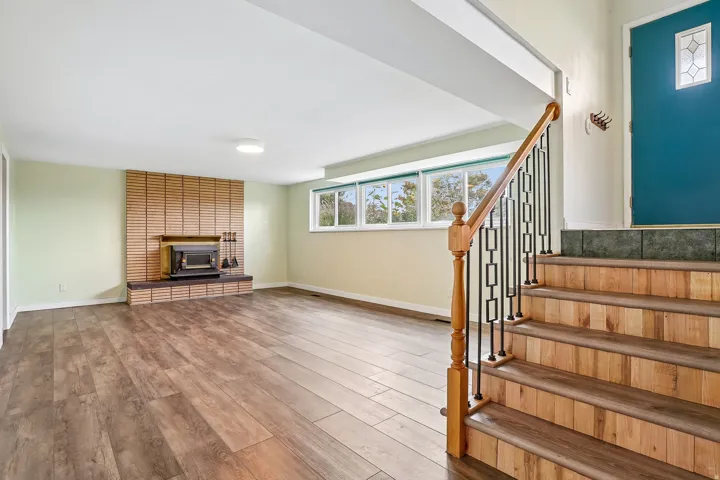 Lower-level living area featuring wood-finish flooring, a brick fireplace, and multiple windows