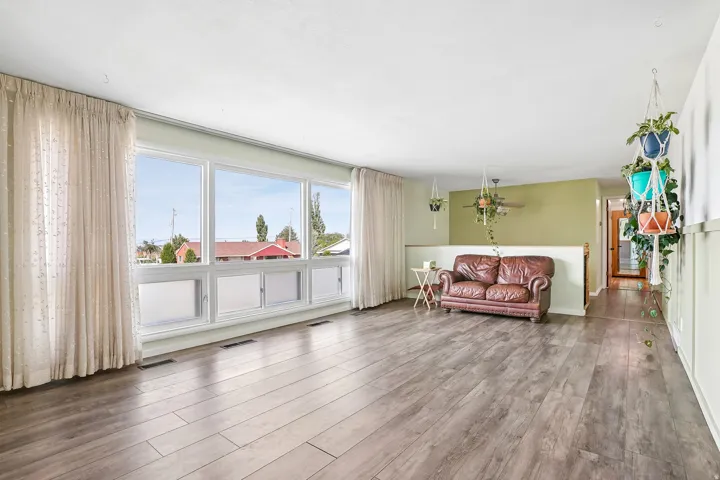 Expansive room featuring wood-finish flooring, a large multi-pane window, and a partial wall with a half-height partition