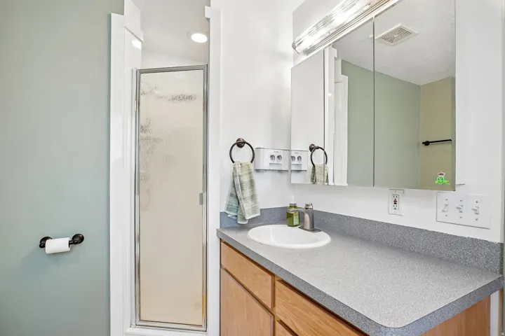 Bathroom vanity with a composite countertop, an integrated sink, and an overhead mirrored medicine cabinet