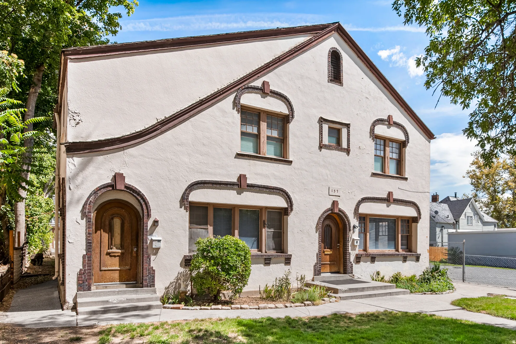 Stucco exterior with decorative brick accents, arched entryways, and multiple window styles