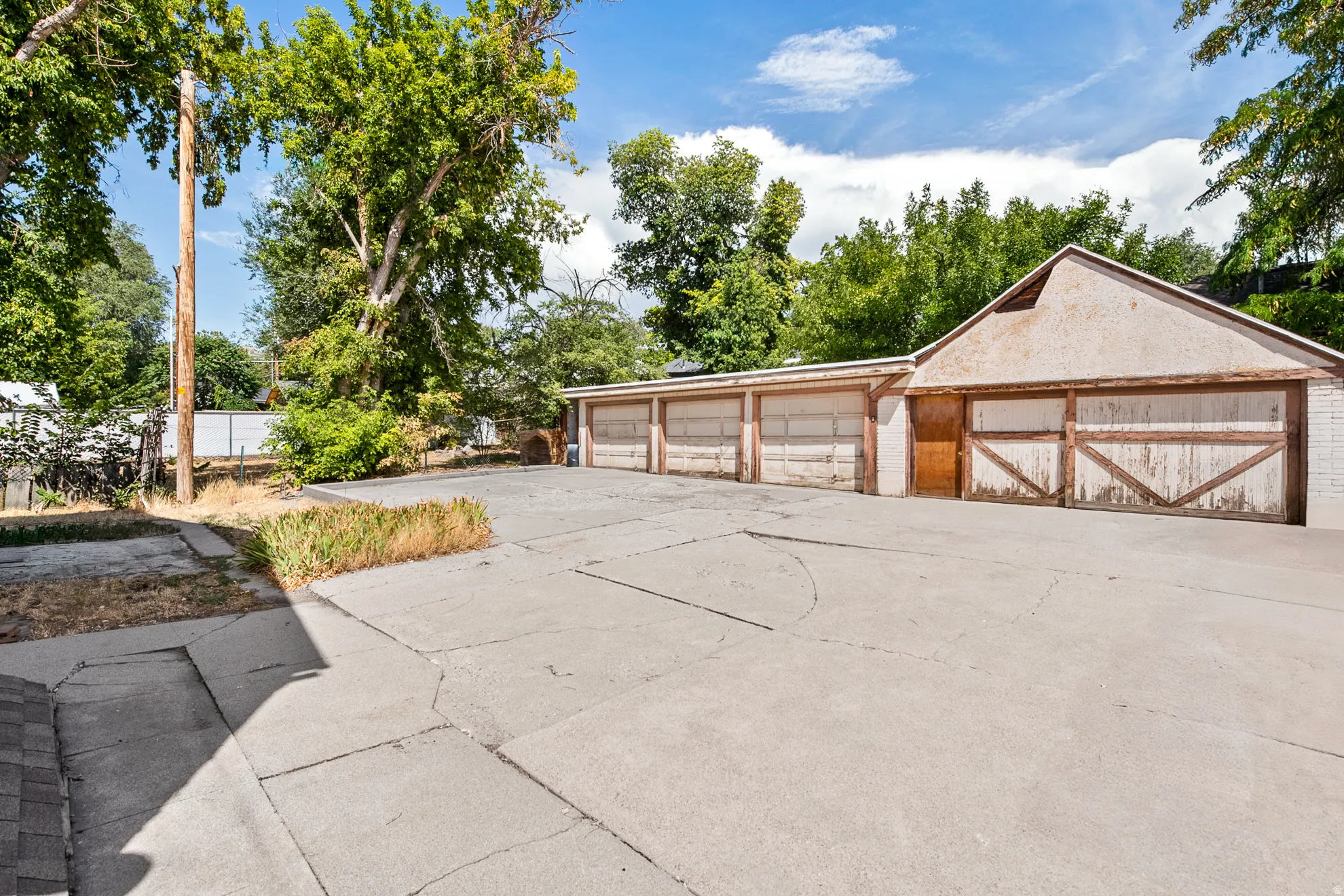 Detached multi-car garage with multiple overhead doors and a pedestrian entry door, complemented by a large paved driveway