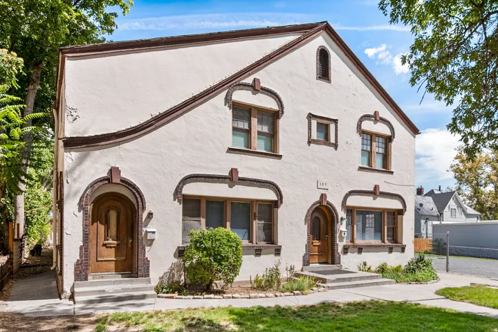 Stucco exterior with decorative brick accents, arched entryways, and multiple window styles
