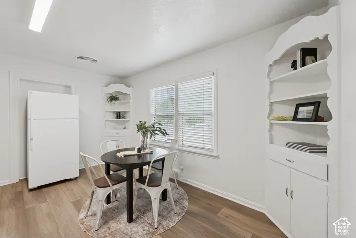 Wood-finish flooring, built-in corner shelving, integrated white refrigerator, and white window blinds