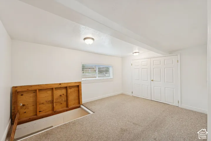 Carpeted flooring, white walls, double panel doors, flush mount lighting, and a window with horizontal blinds